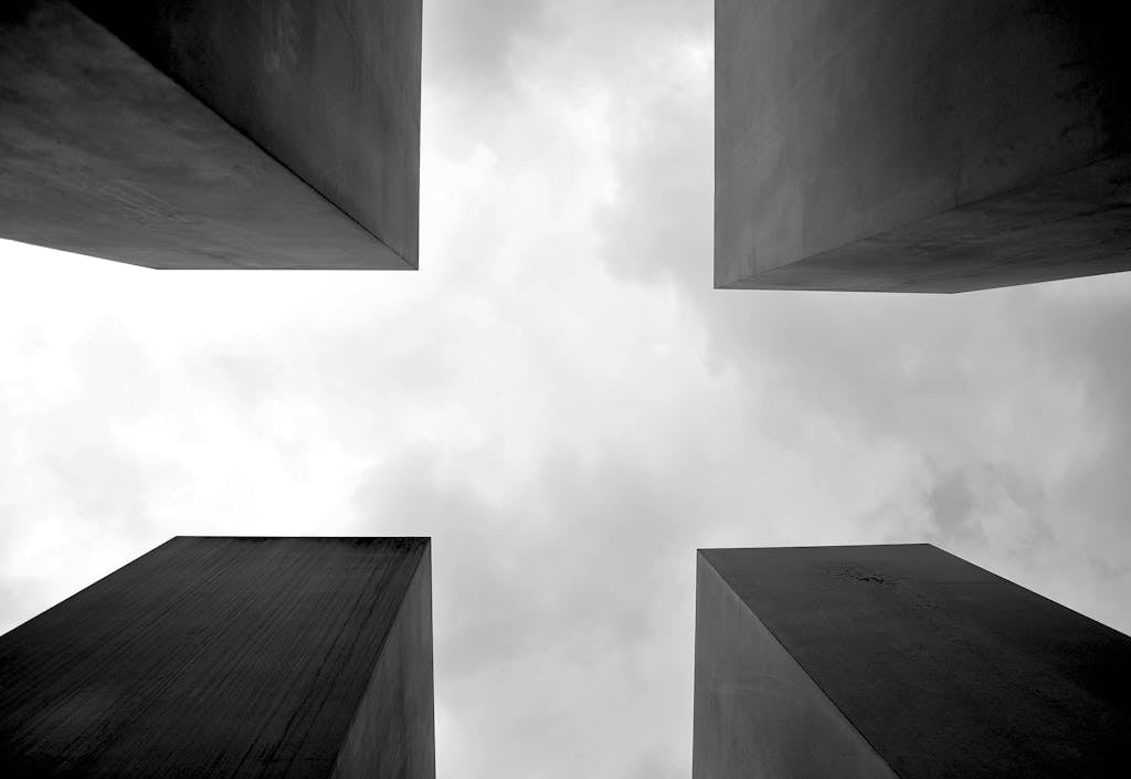 Dramatic black and white photo of towering architectural structures against a cloudy sky.